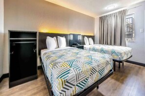 Une chambre d’hôtel avec un lit, un bureau, une armoire et une fenêtre avec des rideaux.