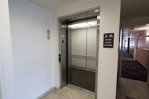 Un ascensor amb un senyal que indica utilitzar les escales en cas d'incendi.