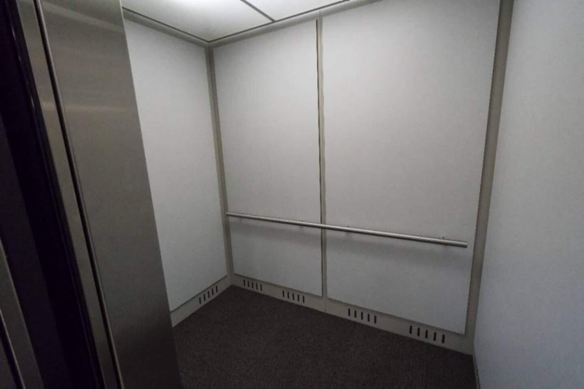 A small, enclosed elevator with a plain white interior and a carpeted floor.