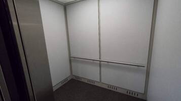 A small, enclosed elevator with a plain white interior and a carpeted floor.