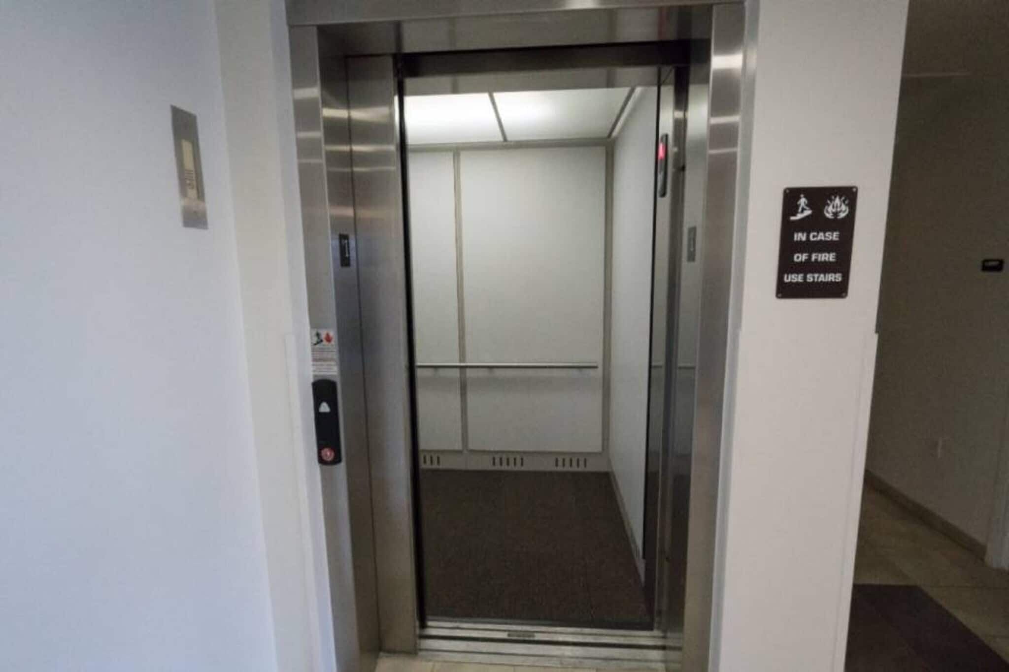 An elevator with a sign indicating use of stairs in case of fire.