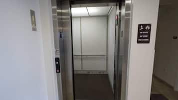 An elevator with a sign indicating use of stairs in case of fire.