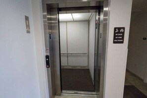 Un ascensor amb un senyal que indica l'ús d'escales en cas d'incendi.