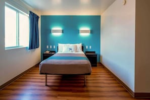 Habitació d'hotel amb un llit, dues taules de nit, una finestra amb cortines i una paret d'accent blava.