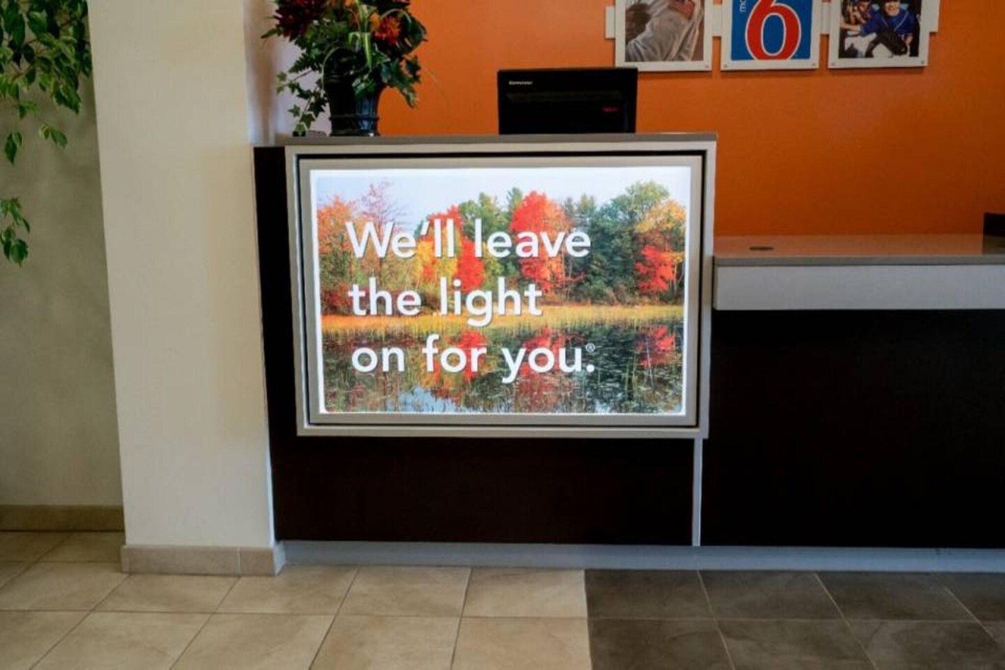 A reception desk with a framed message and a vase of flowers.