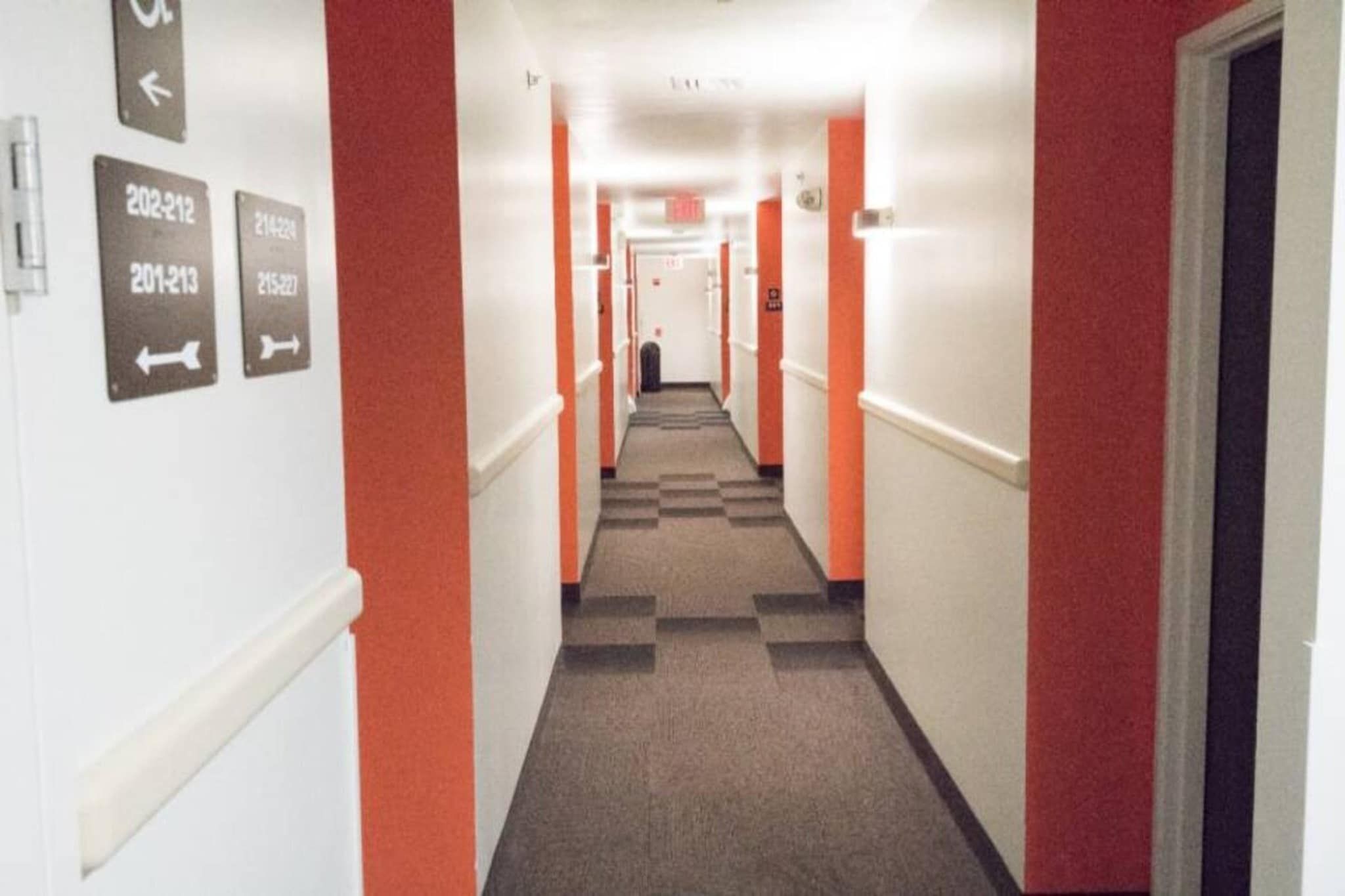 A hotel corridor with directional signs and a check-in counter at the end.