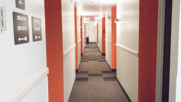 A hotel corridor with directional signs and a check-in counter at the end.