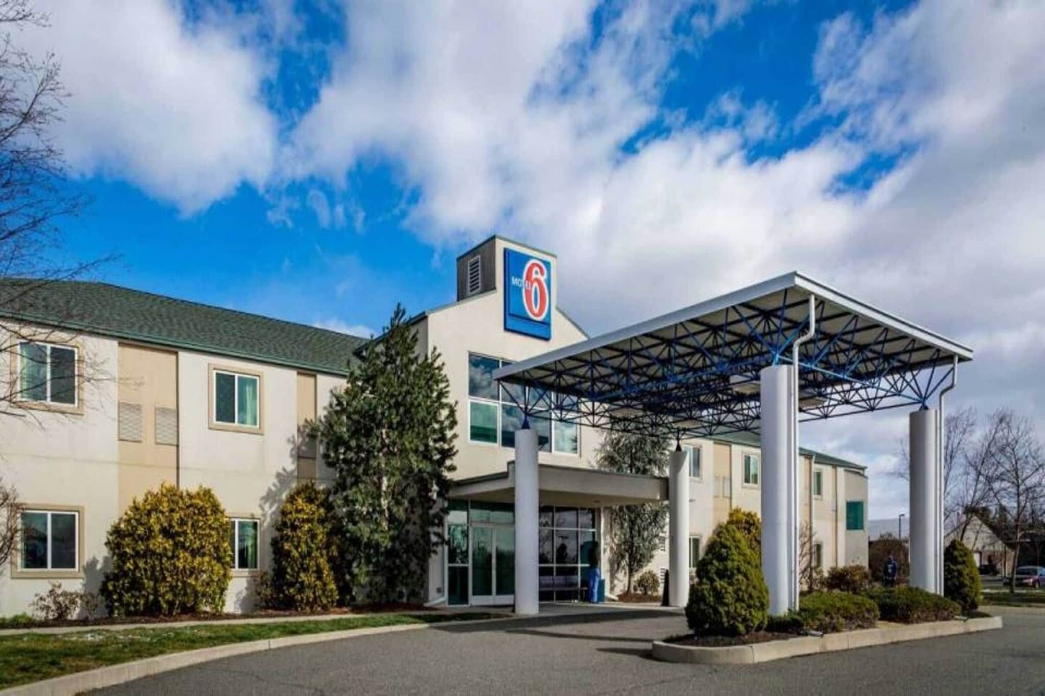 A hotel with a covered entrance, a prominent '6' sign, and a parking lot.
