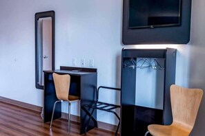 Habitació d'hotel amb escriptori, dues cadires, paraigua i televisió penjada a la paret.