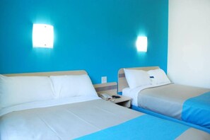Habitació d'hotel amb dos llits, una taula de nit i una làmpada penjada a la paret.