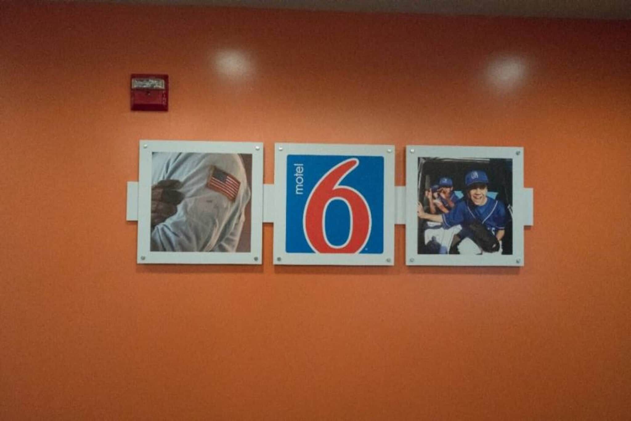 Een muur met drie decoratieve objecten: een vlag, een motelteken en een groepsfoto.