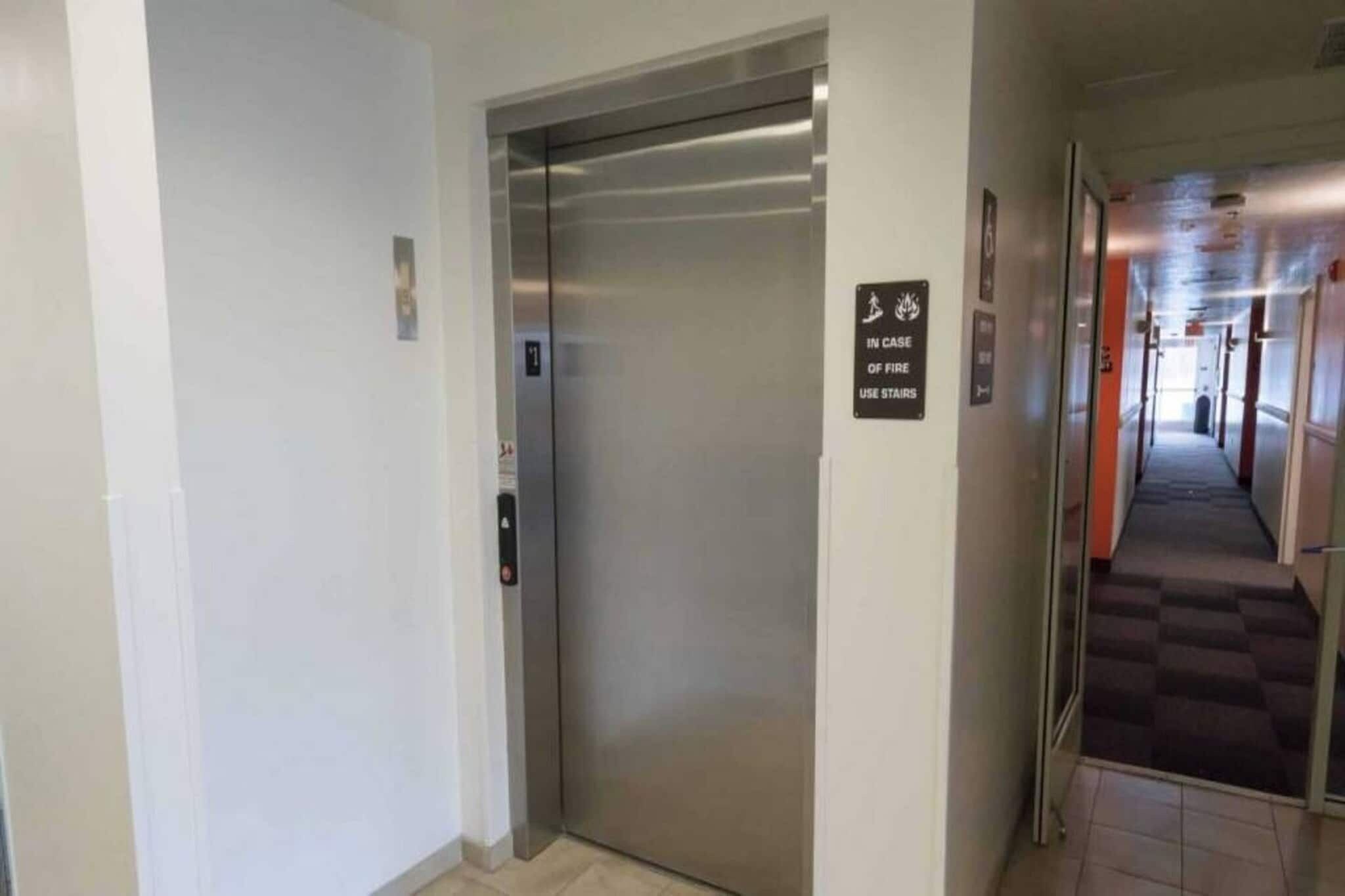 An elevator with a sign indicating use of stairs in case of fire.