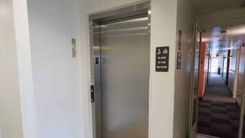 An elevator with a sign indicating use of stairs in case of fire.