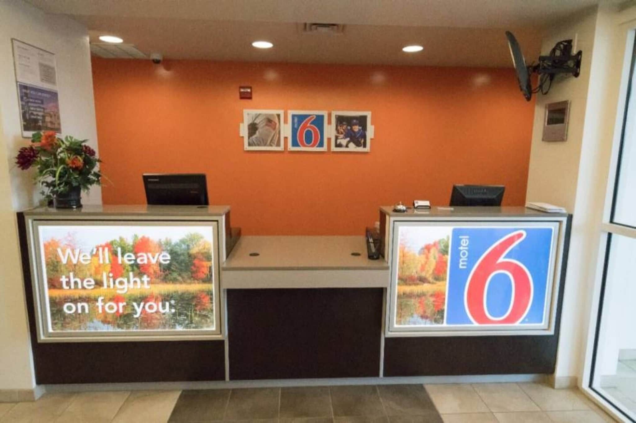 A reception desk with a large number '6' sign, a flower vase, and a framed picture on the wall.