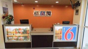 A reception desk with a large number '6' sign, a flower vase, and a framed picture on the wall.