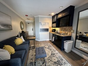 A compact living space with a kitchenette, a sofa with cushions, a patterned rug, and a large mirror. - Ski In and Ski Out Park City Canyons- 3501B (Park City)