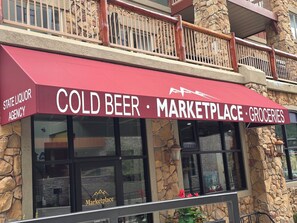 A storefront with a red awning labeled 'COLD BEER MARKETPLACE • GROCERIES' and a stone facade. - Ski In and Ski Out Park City Canyons- 3501B (Park City)