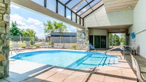 Una piscina con soffitto in vetro, colonne in pietra e vista sulla zona circostante.