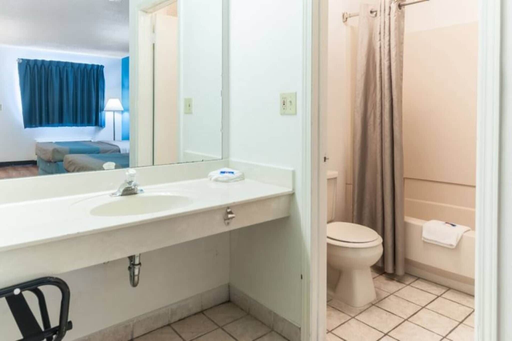 A bathroom with a sink, mirror, toilet, and shower curtain.