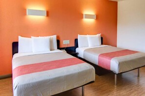 A hotel room with two beds, each with white bedding and a red accent.