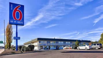 Un motel con un letrero llamativo que indica '6 WI FI HERE' y un cielo azul despejado.