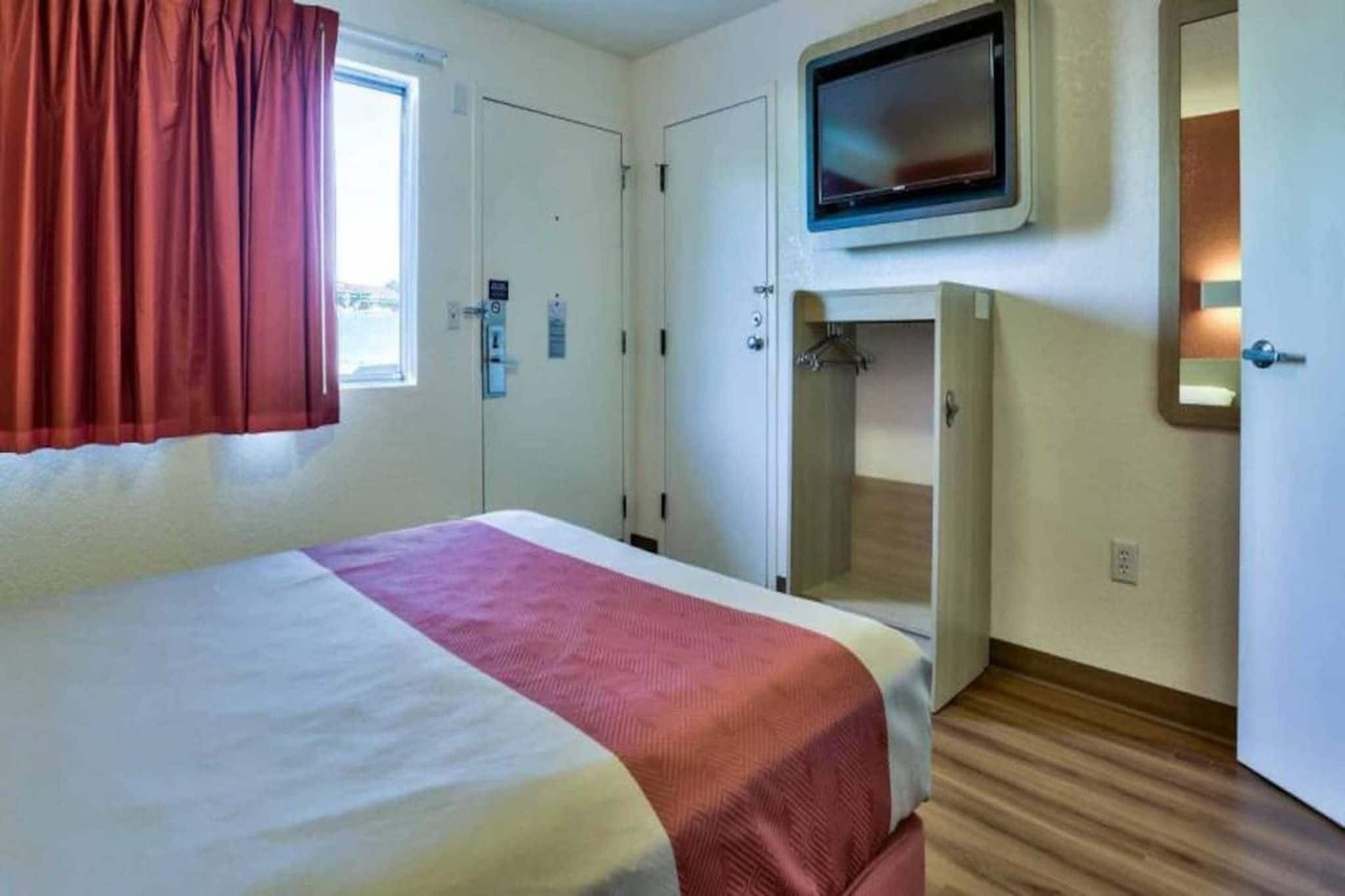 A hotel room with a bed, a television, a wardrobe, and a shower area.