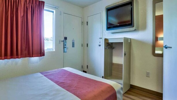 Quarto de hotel com cama, televisão, guarda-roupa e zona de duche.