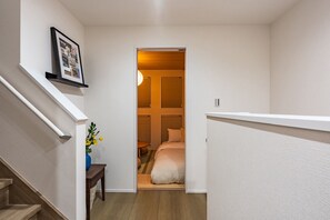 A hallway leading to a bedroom with a bed, a bedside table, and a framed photo on the wall. - Nikyo Sumimaru Hikari Private Villa (Osaka)