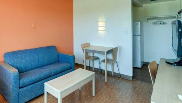Espaço compacto para viver, com sofá azul, mesa pequena, cozinha compacta e área de refeições.