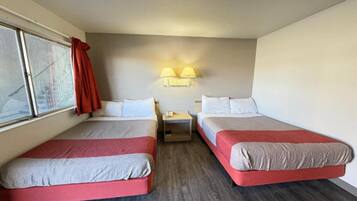 Een hotelkamer met twee bedden, een nachtkastje en een raam met gordijnen.