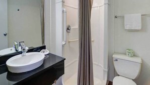 Casa de banho com lavatório branco, espelho, cabine de duche e sanita.