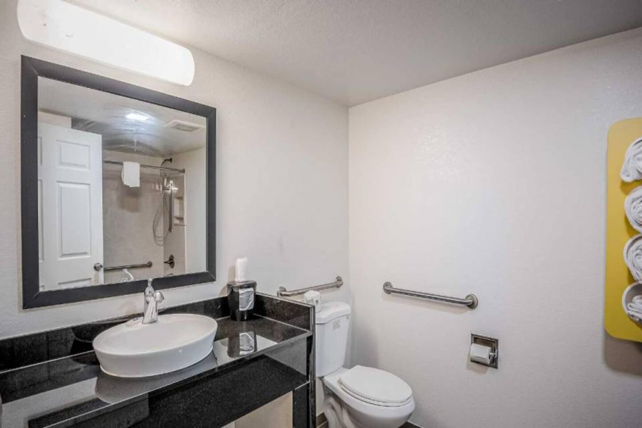A bathroom with a sink, mirror, toilet, and a shower stall.