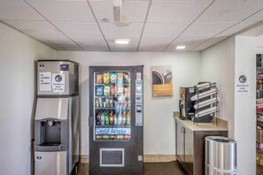 Màquina expenedora amb una varietat de llaminatures i begudes fredes, un dispensador d'aigua i una cafetera.