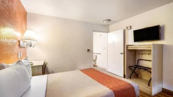 Ein Hotelzimmer mit Bett, Schreibtisch, Wandfernseher und Kleiderschrank.