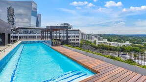 Una piscina en la azotea con vistas a edificios circundantes y un cielo despejado.