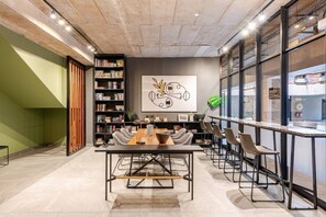 Ein modernes Interieur mit Konferenztisch, Stühlen, einem Bücherregal und einem großen abstrakten Gemälde.