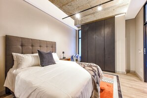 Un dormitorio moderno con una cama grande, un armario oscuro y vistas al exterior.