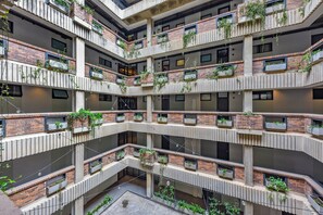 Un edificio de varios niveles con balcones, cada uno adornado con plantas en macetas.