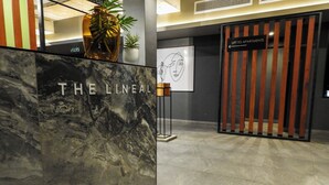 Una recepción con la señalización "THE LINEAL", una planta en maceta y un letrero que indica "LIFT TO APARTMENTS".