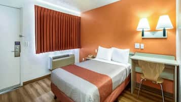 Ein Hotelzimmer mit Bett, Nachttisch, Lampe und Klimaanlage.