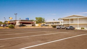 Un estacionamiento con un motel y una gasolinera al fondo.