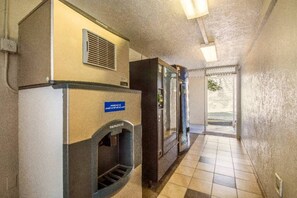 A hallway with a vending machine, a refrigerator, and a door leading to an outdoor area. - 1 Queen Bed | Youngtown (Youngtown)
