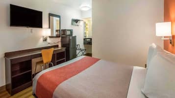 A hotel room with a bed, a desk, a chair, a television, and a mirror.