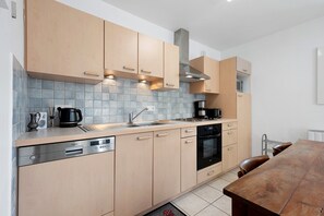 A modern kitchen with light wood cabinets, a stainless steel dishwasher, a built-in oven, and a coffee maker. - 'St Colomban Des Villard' Apartment with Mountain View and Private Terrace (Saint-Colomban-des-Villards)