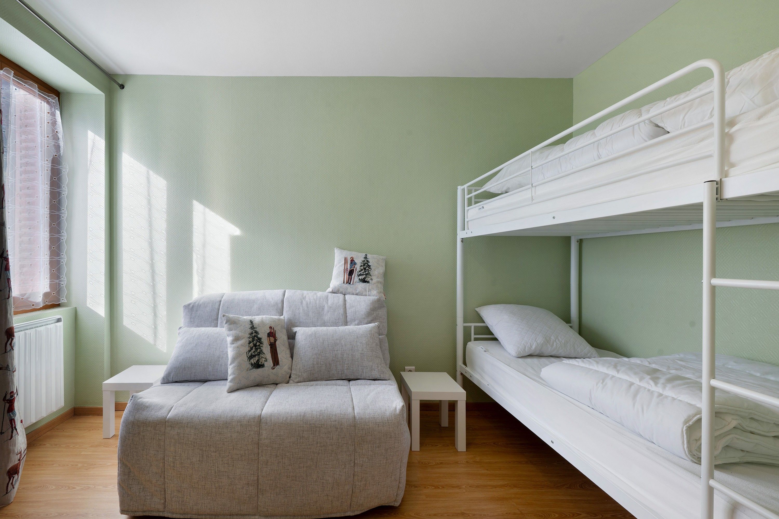 A room with a bunk bed, a daybed, and a small table.