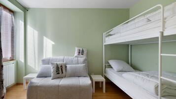 A room with a bunk bed, a daybed, and a small table.