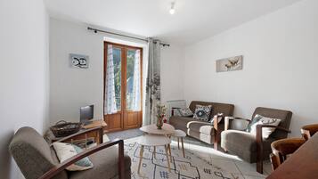 A living room with a sofa, armchairs, a coffee table, a TV, and a patterned rug.