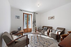 A living room with a sofa, armchairs, a coffee table, a TV, and a patterned rug. - 'St Colomban Des Villard' Apartment with Mountain View and Private Terrace (Saint-Colomban-des-Villards)