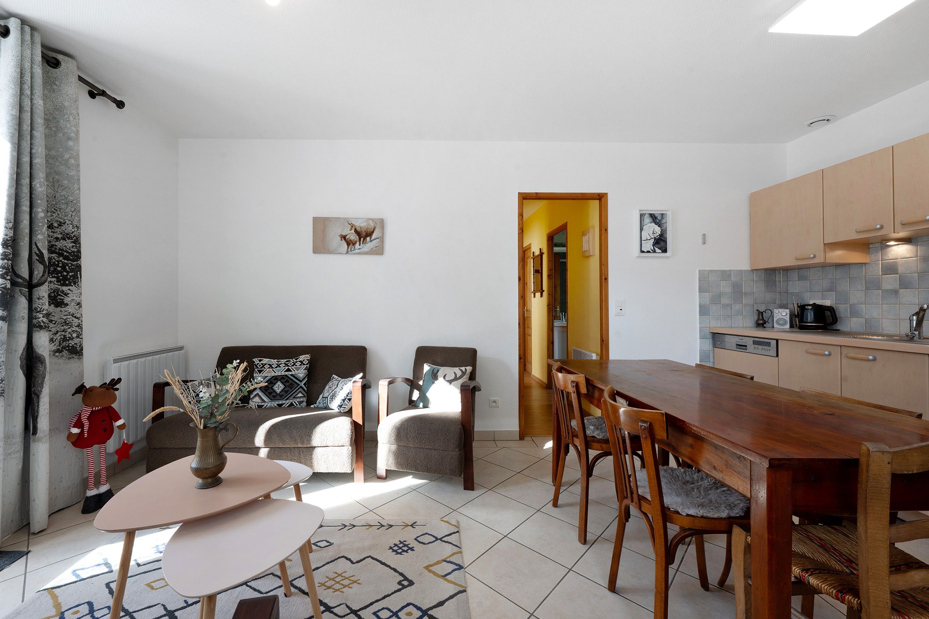 Un espai de vida modern amb zona de menjador, cuina i un ambient acollidor amb coixins estampats.