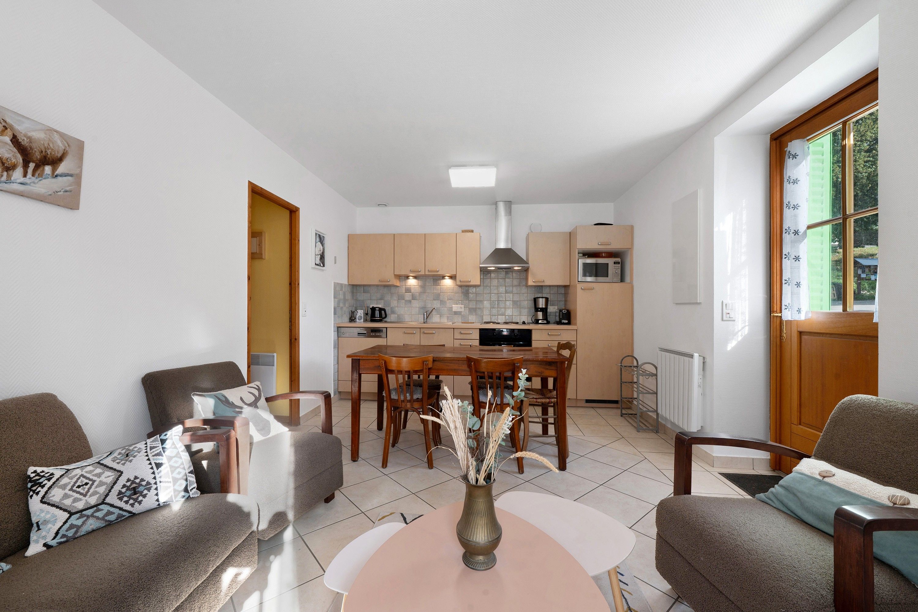 A modern kitchen with wooden cabinets, a central island, and a dining area with chairs.
